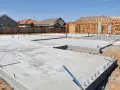 Fundament domu w budowie, widać beton na chudziaka, zbrojenie i szkielet drewniany przyszłego budynku.