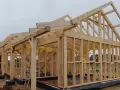 Drewniana konstrukcja domu w budowie, zgodna z kanadyjskimi projektami. Widać szkielet ścian i dachu, gotowy do dalszych prac.