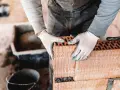 Budowlaniec w białych rękawiczkach układa pustak keramzytobetonowy, tworząc ścianę.