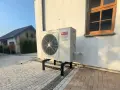 Pompa ciepła Aiwa Inverter R32 na stelażu przed budynkiem. Zastanawiasz się, jaką pompę ciepła wybrać?