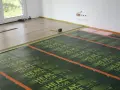 Montaż ogrzewania podłogowego na drewnianym stropie. Folie grzewcze HEAT DECOR rozłożone na podłodze, gotowe do położenia paneli.