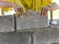 Budowniczy układa bloczek betonowy, zastanawiając się, ile waży bloczek betonowy.