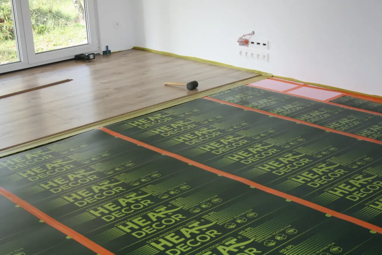 Montaż ogrzewania podłogowego na drewnianym stropie. Folie grzewcze HEAT DECOR rozłożone na podłodze, gotowe do położenia paneli.