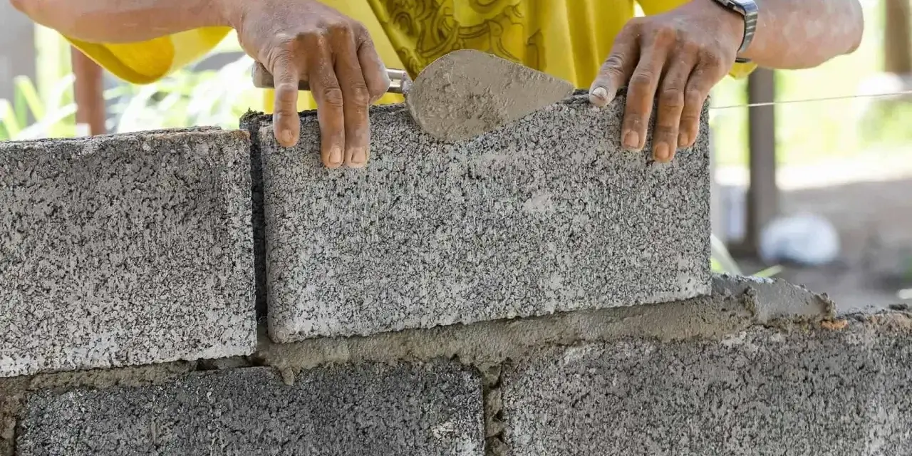 Budowniczy układa bloczek betonowy, zastanawiając się, ile waży bloczek betonowy.