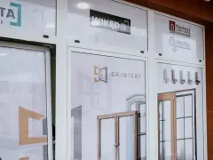 Witryna salonu okien i drzwi z logotypami firm i zdjęciami produktów.