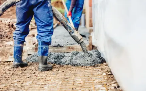 Pracownicy wylewają beton na zbrojenie. Sprawdź aktualny suchy beton cena 1m3.