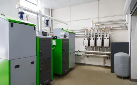 Pomieszczenie techniczne z kotłami, rurami i manometrami.