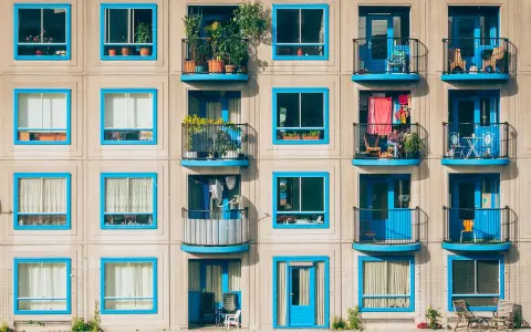 Elegancka loggia i balkon z niebieskimi ramami okiennymi na betonowej fasadzie budynku.