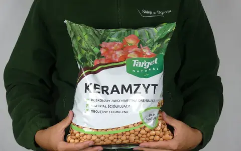 Osoba trzyma worek z napisem "Keramzyt", który jest doskonałym materiałem drenażowym i ściółkującym.