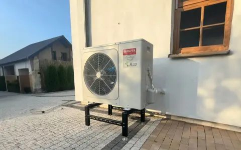 Pompa ciepła Aiwa Inverter R32 na stelażu przed budynkiem. Zastanawiasz się, jaką pompę ciepła wybrać?