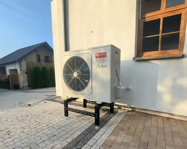Pompa ciepła Aiwa Inverter R32 na stelażu przed budynkiem. Zastanawiasz się, jaką pompę ciepła wybrać?