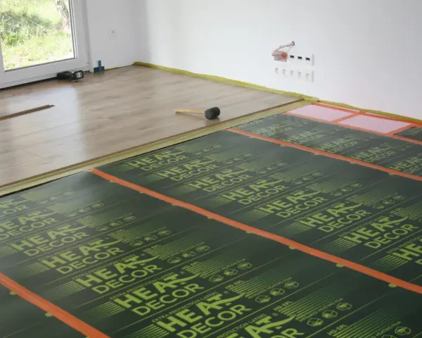 Montaż ogrzewania podłogowego na drewnianym stropie. Folie grzewcze HEAT DECOR rozłożone na podłodze, gotowe do położenia paneli.