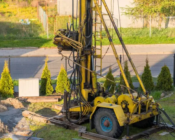Żółta wiertnica na podwórku. Zastanawiasz się, ile kosztuje wykopanie studni głębokości 25 m?