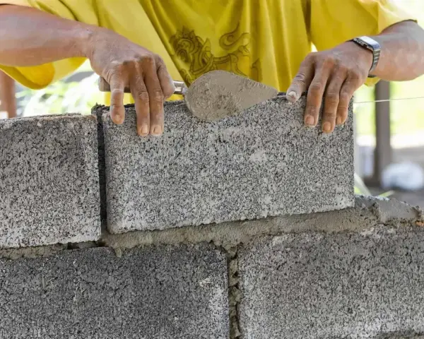 Budowniczy układa bloczek betonowy, zastanawiając się, ile waży bloczek betonowy.