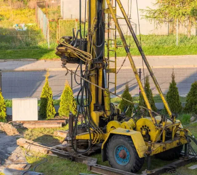 Żółta wiertnica na podwórku. Zastanawiasz się, ile kosztuje wykopanie studni głębokości 25 m?