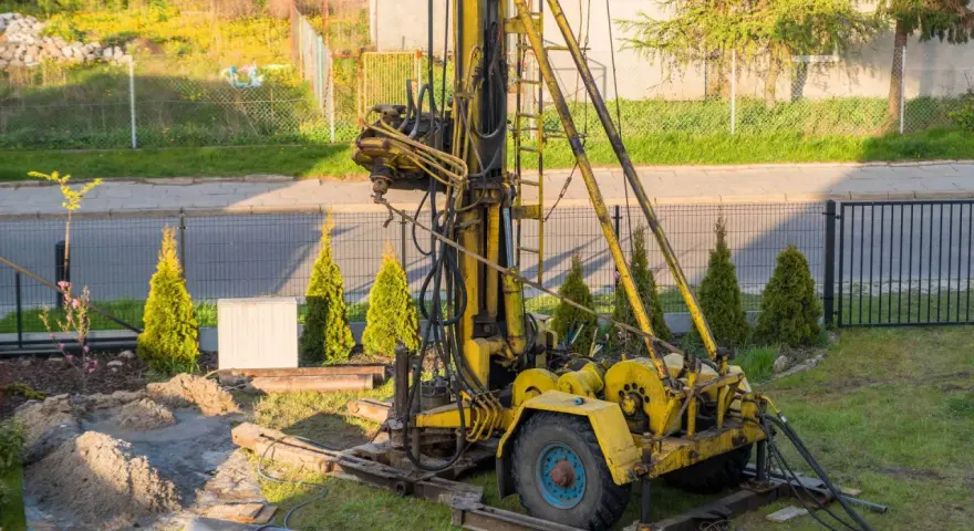 Żółta wiertnica na podwórku. Zastanawiasz się, ile kosztuje wykopanie studni głębokości 25 m?